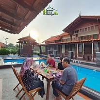Keluarga menjamu selera di tepi kolam
